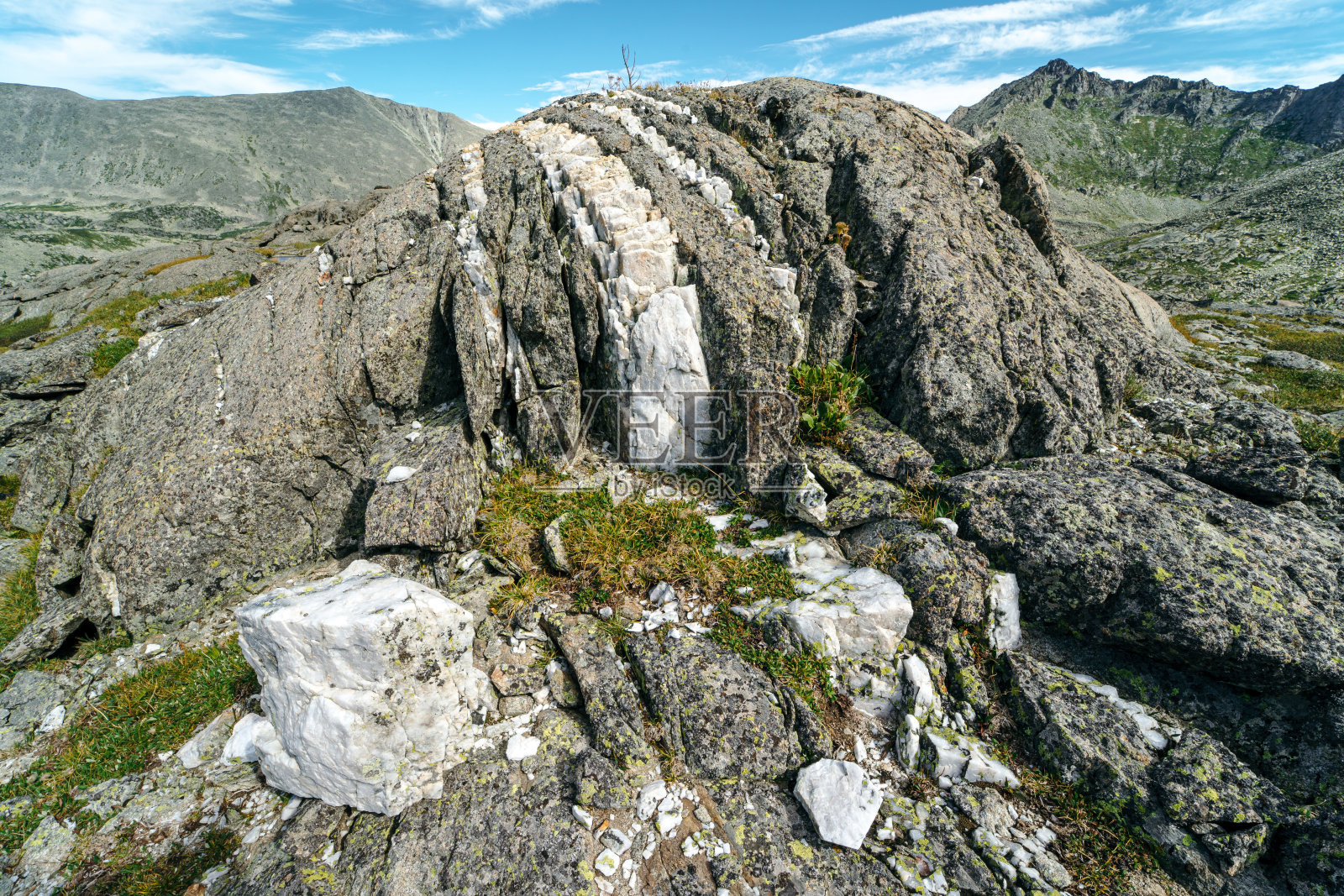 岩石里面有一层白色大理石。山区地质勘查。照片摄影图片