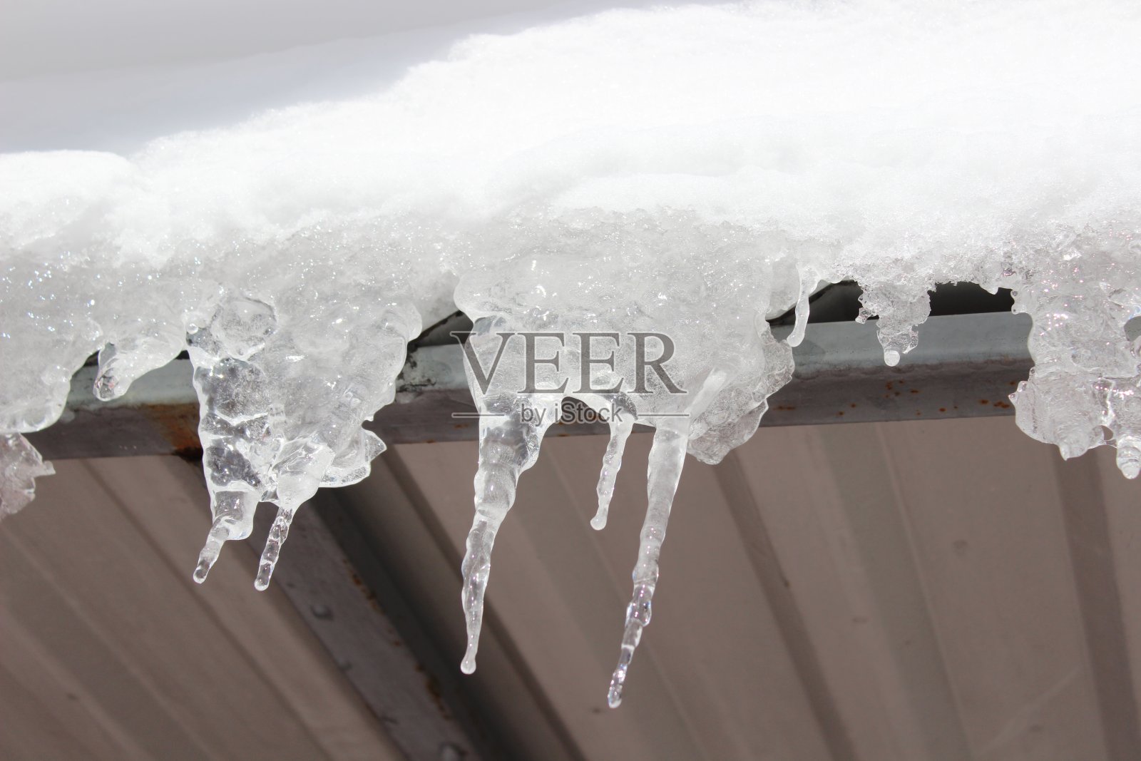 屋顶上有雪的冰柱，形状有趣照片摄影图片