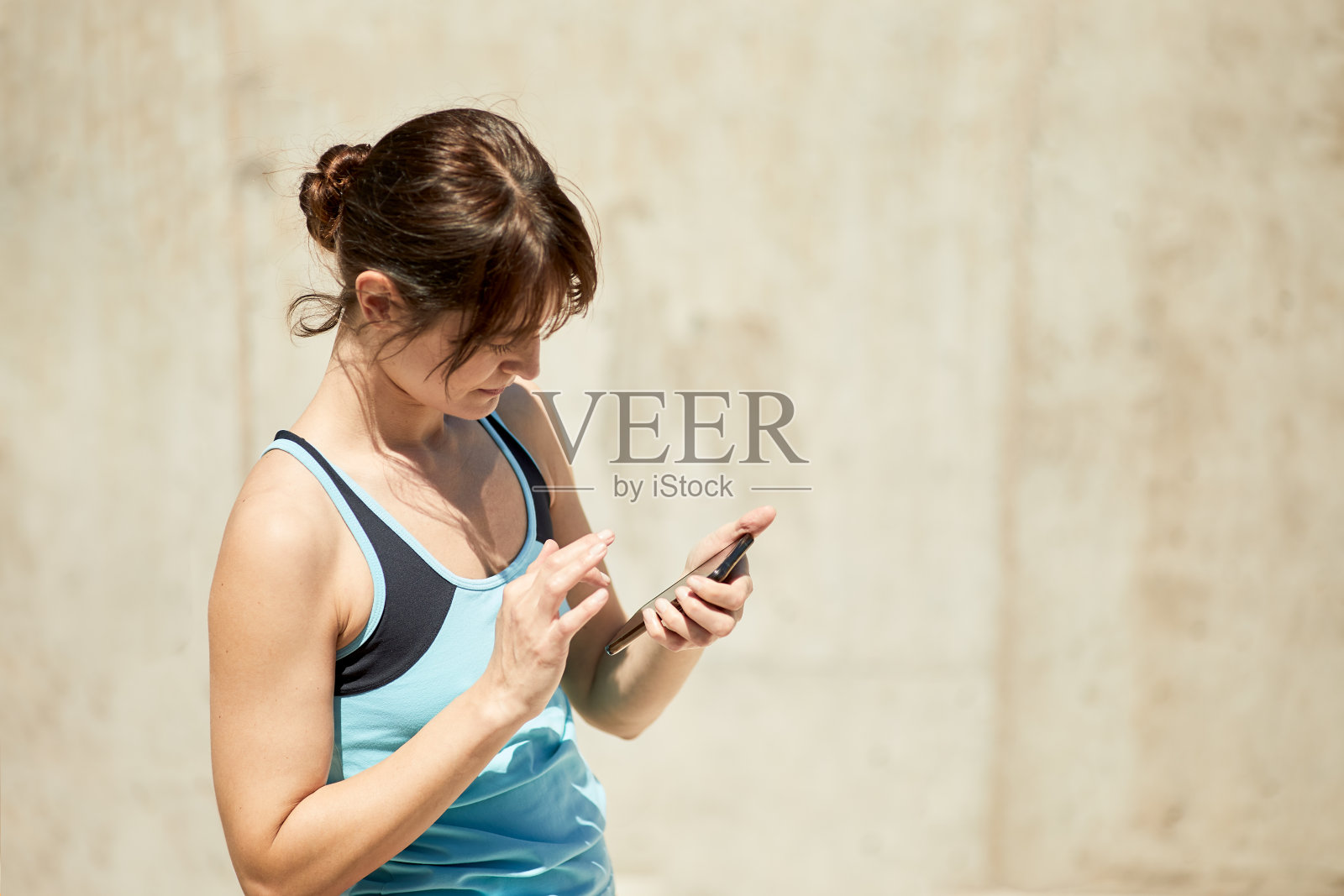 年轻的西班牙女性在使用移动健身应用程序。照片摄影图片