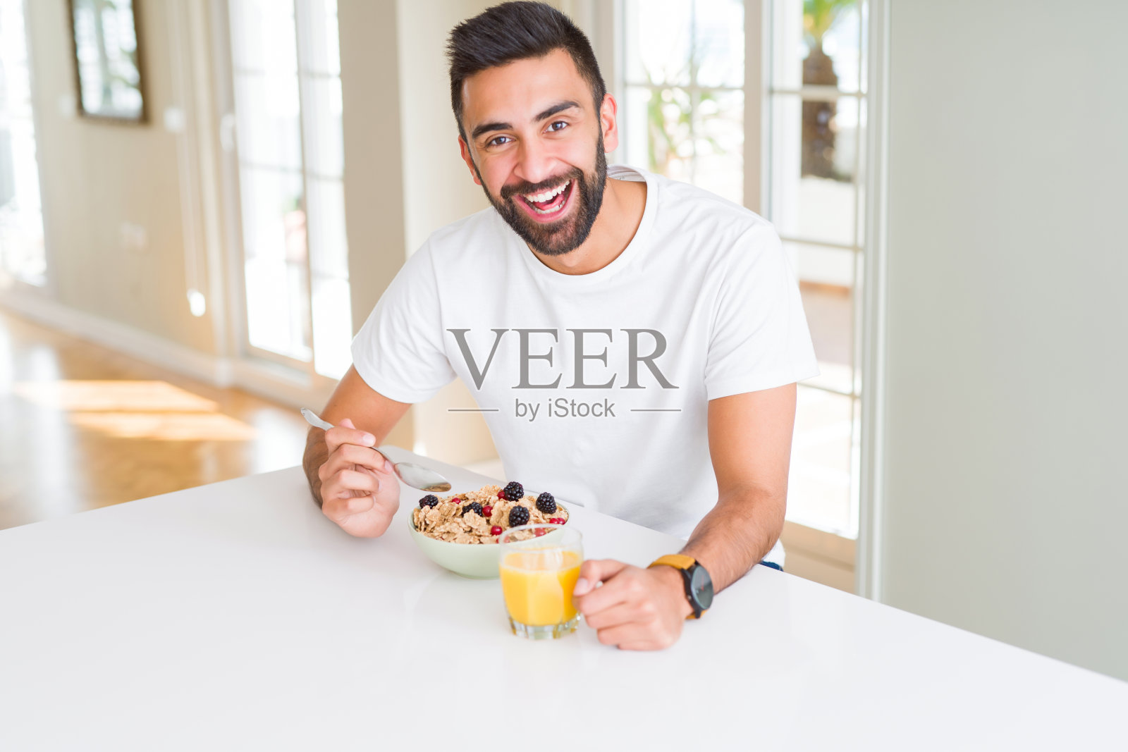 英俊的男人微笑着吃健康的早餐，早上喝橙汁照片摄影图片