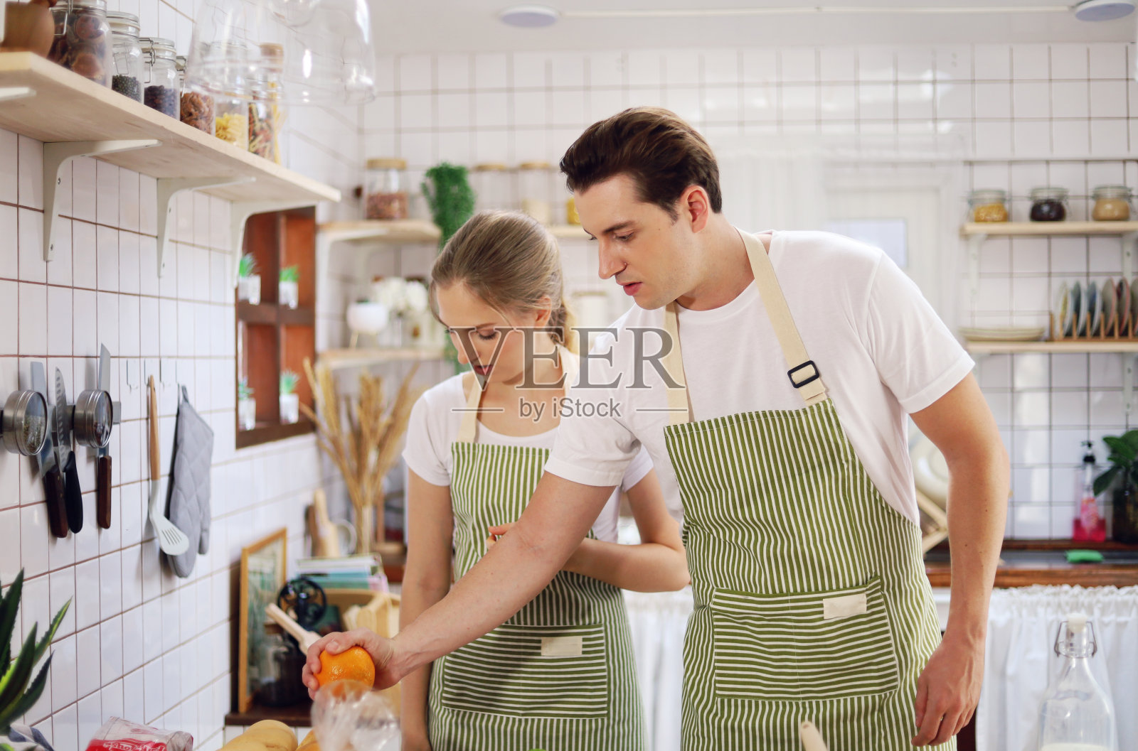 年轻的恋人正在家里的厨房里准备做饭。照片摄影图片