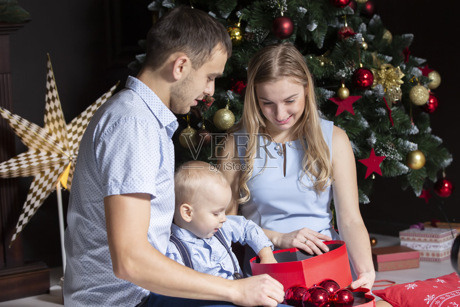 家庭在圣诞节。爸爸妈妈和儿子在圣诞树旁照片摄影图片