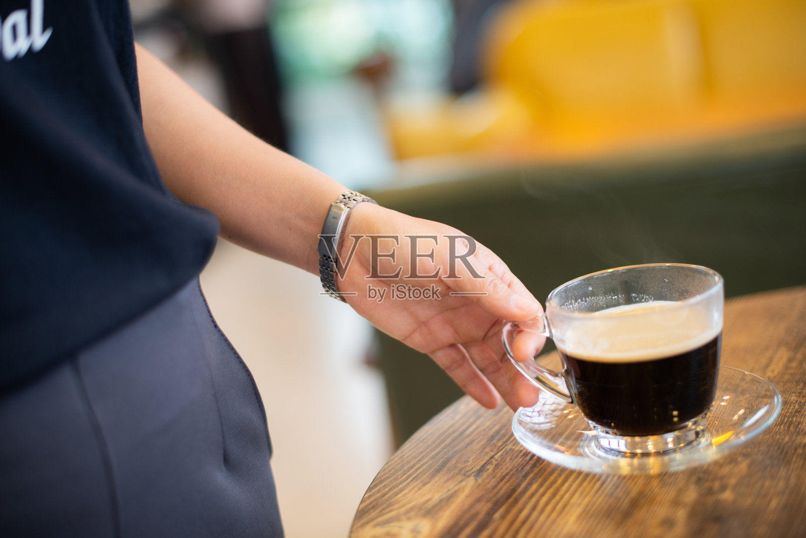 一个女人在桌子上拿着一个热的黑咖啡杯照片摄影图片