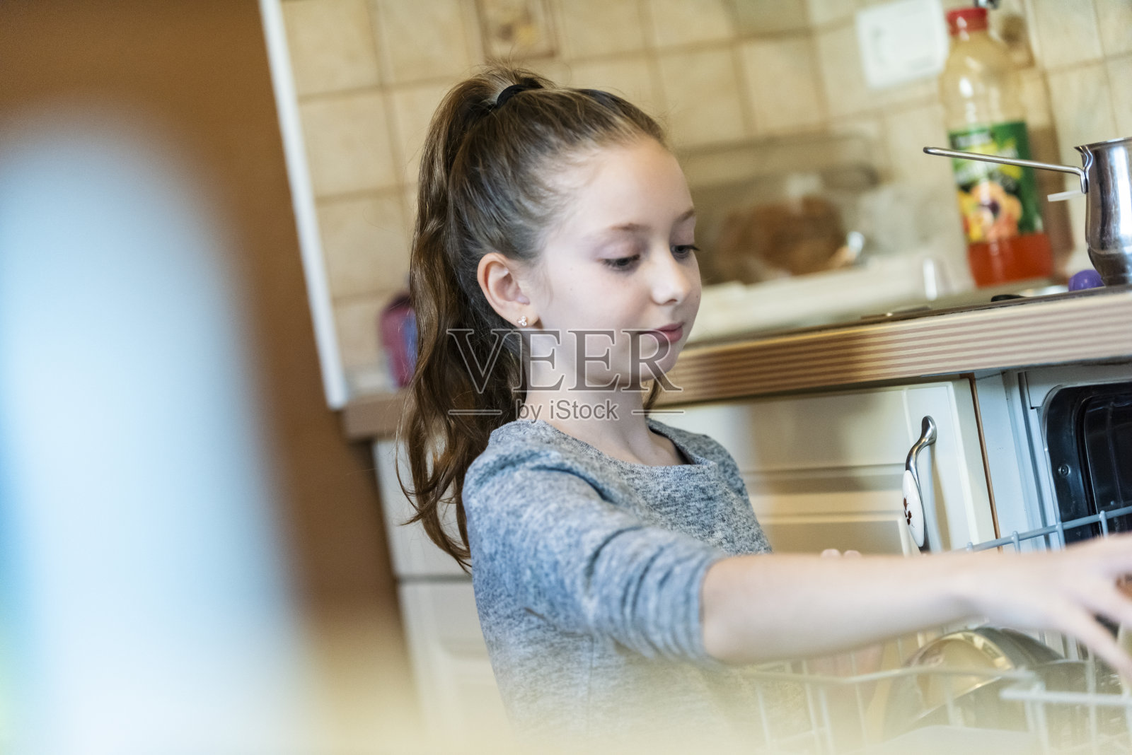 把盘子放进洗碗机的少女照片摄影图片