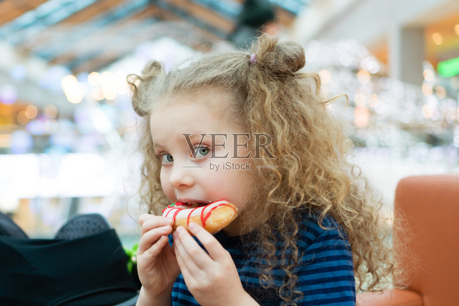 小女孩在商场里嚼甜甜圈照片摄影图片