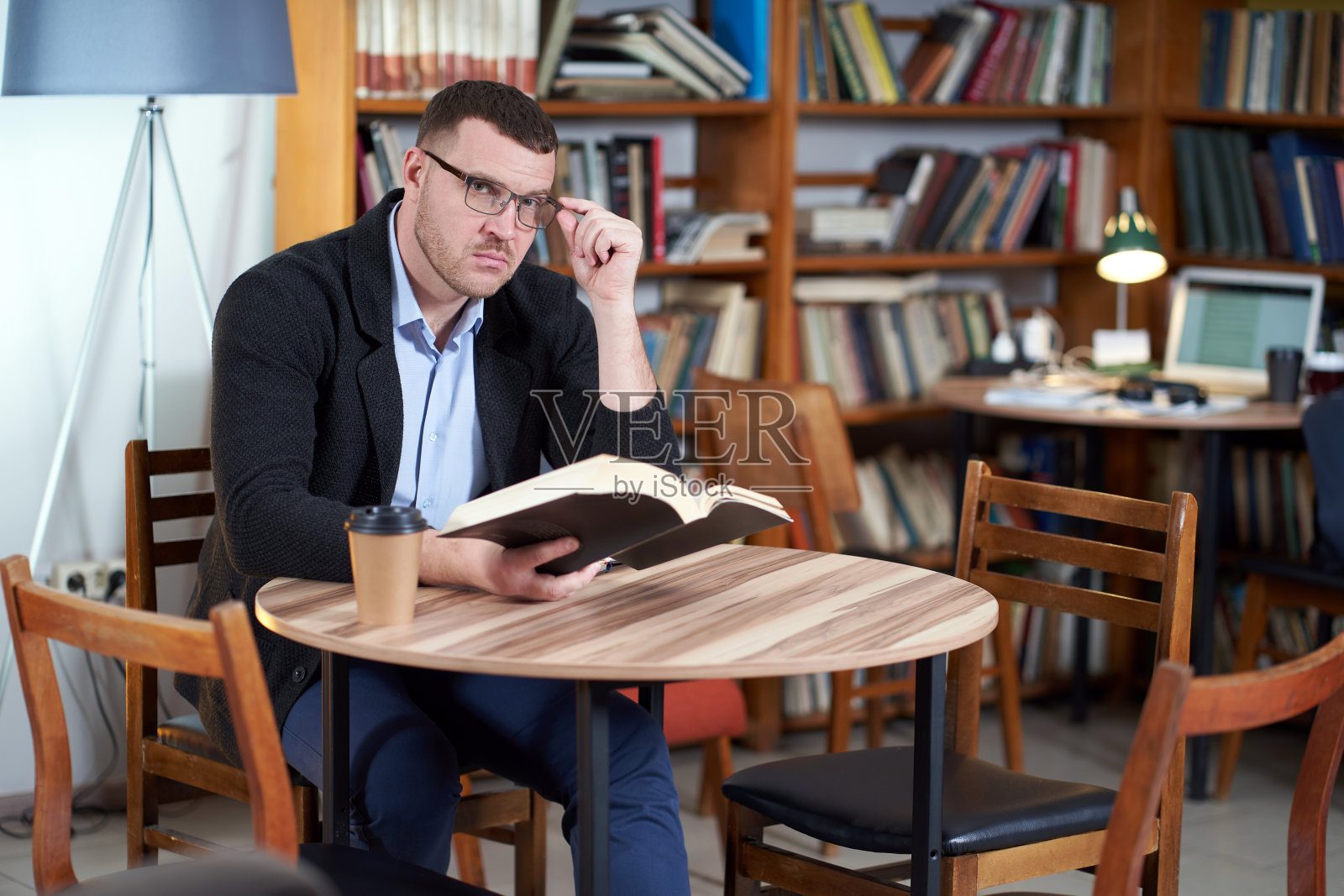 一个人在图书馆的咖啡馆里看书和喝咖啡，有很多书作为背景照片摄影图片