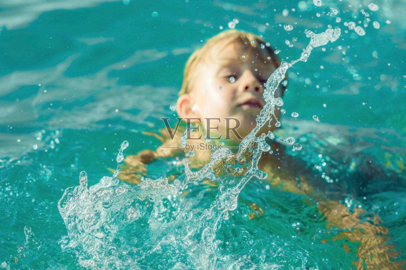 男孩在蓝色的热带海洋里游泳。炎热的夏天照片摄影图片