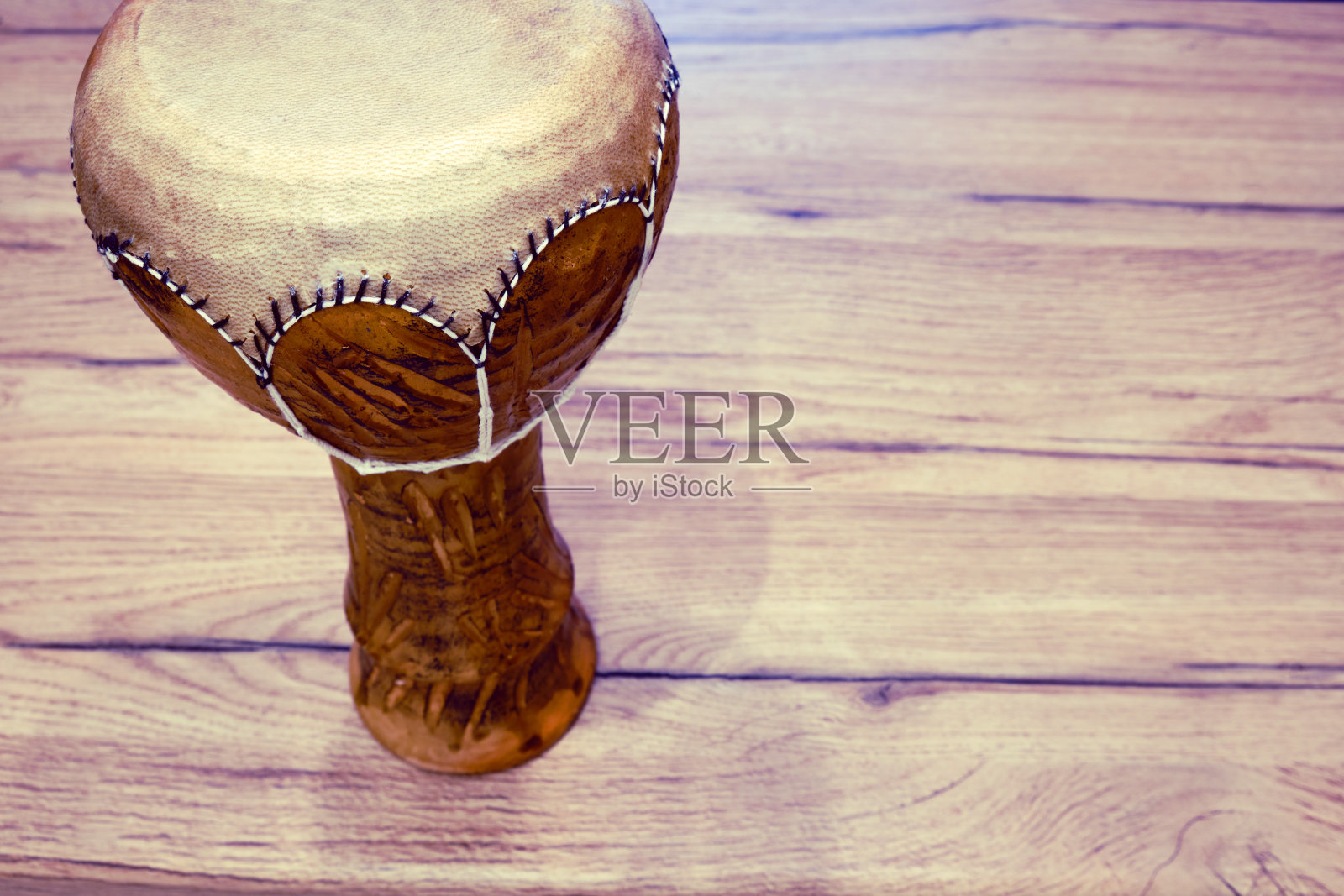 传统的突尼斯鼓，用粘土和骆驼皮制成。粘土鼓与皮革膜在木桌上，复制文字空间照片摄影图片