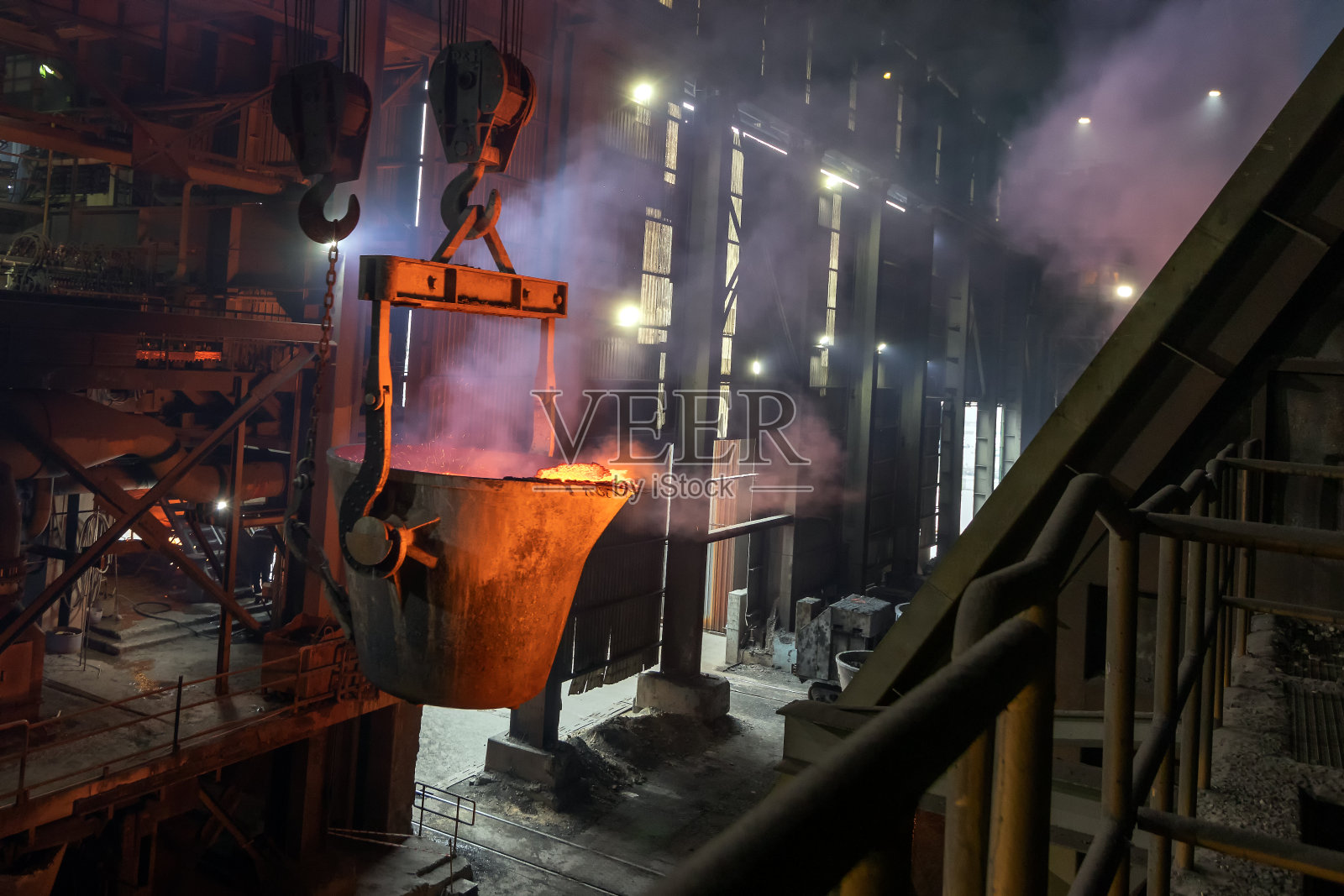 在工厂里，这个大熔炉正在为金属铸件浇铸钢质金属。铸造是一种制造过程，通常将液体材料倒入模具中。照片摄影图片