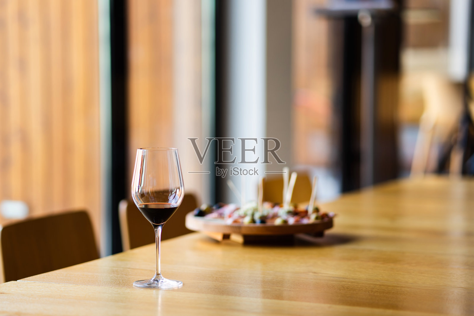 在家里或餐厅的餐桌上，在窗边散光模糊的开胃菜前，放上一杯红酒照片摄影图片
