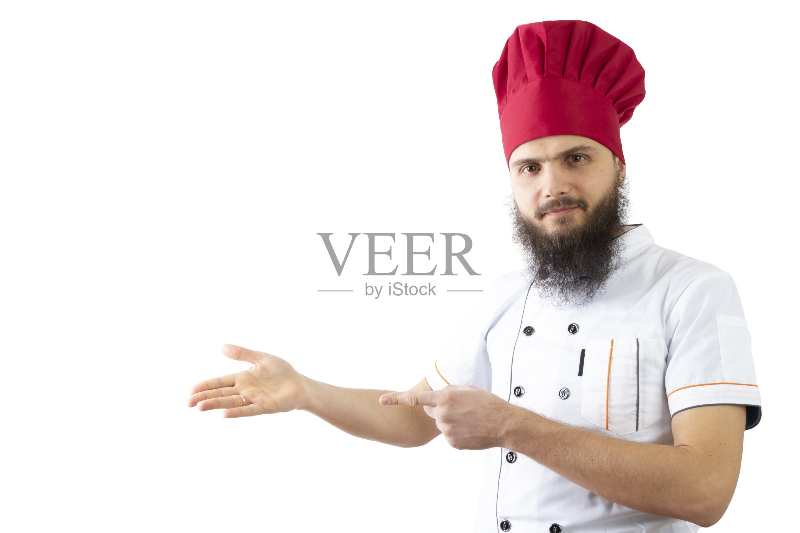 厨师用双手指着一个空地方。留着胡子的男厨师头戴红帽子，身穿白衬衫，在白色背景下独处。脸上露出一丝微笑。复制广告空间。前视图照片摄影图片