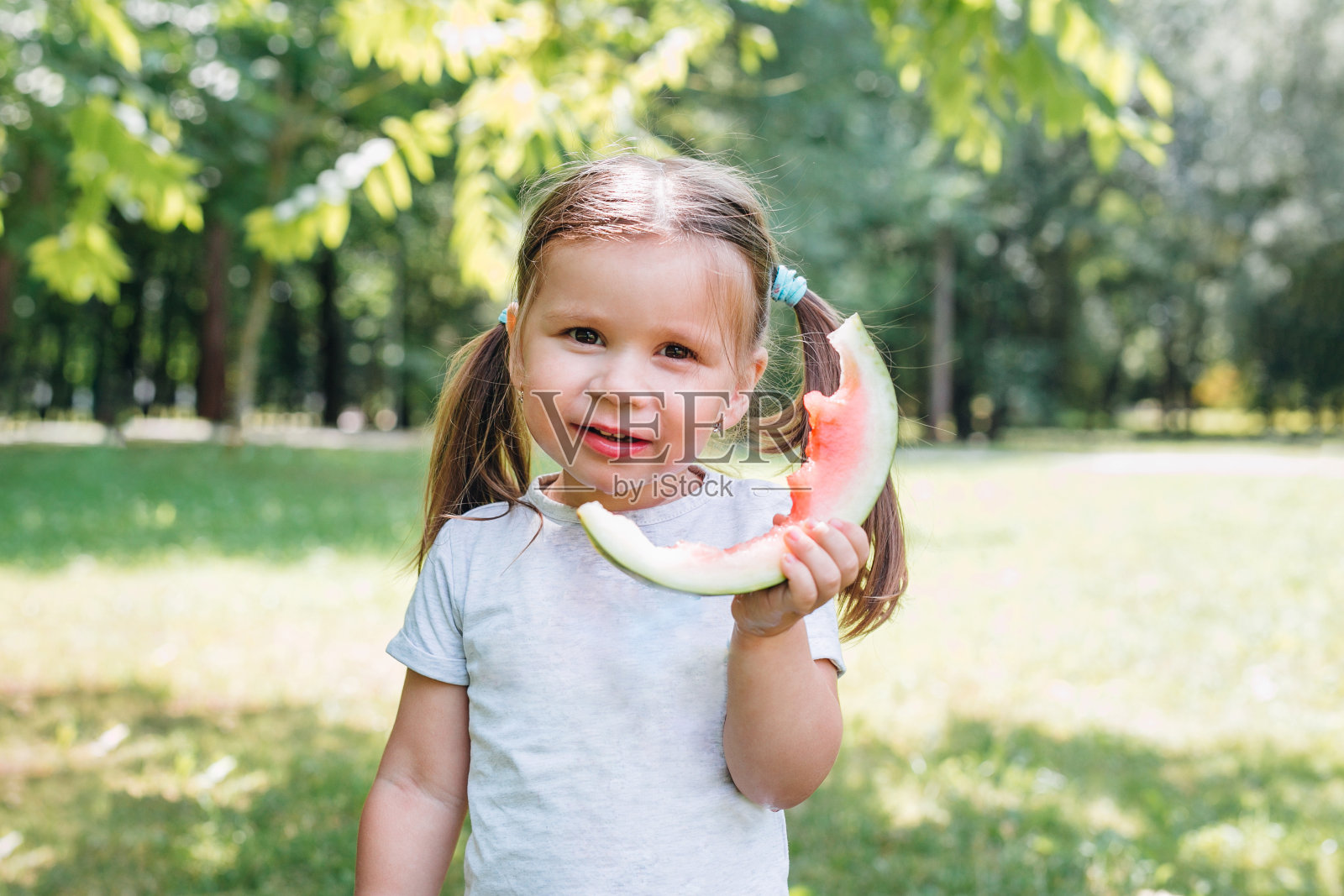 快乐的孩子在夏天的公园吃西瓜照片摄影图片