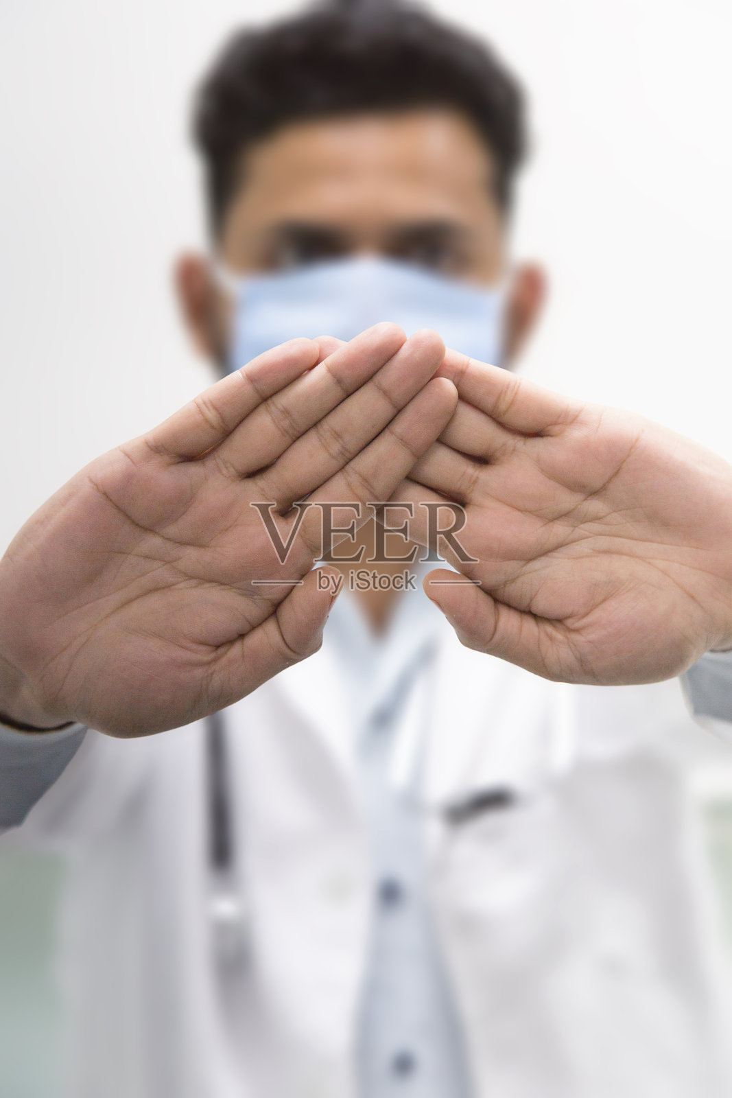 亚洲男医生戴口罩预防2019冠状病毒，站起来并举手，在白色背景上显示错误孤立的符号。照片摄影图片