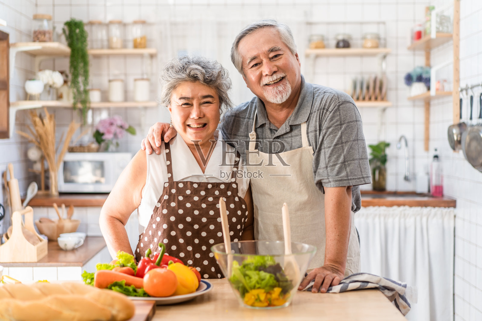 夫妇老亚洲长者幸福生活在家庭厨房。爷爷和奶奶一起煮沙拉菜，快乐地微笑着一起享受退休生活。老年人的关系和活动。照片摄影图片