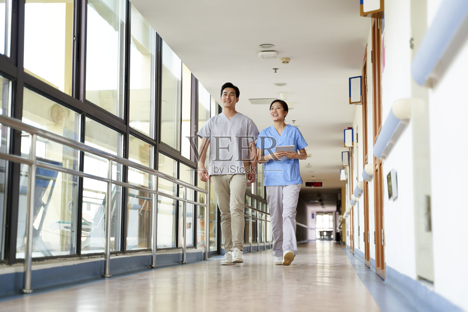 年轻的亚洲医疗工作者同事走在医院走廊上交谈照片摄影图片