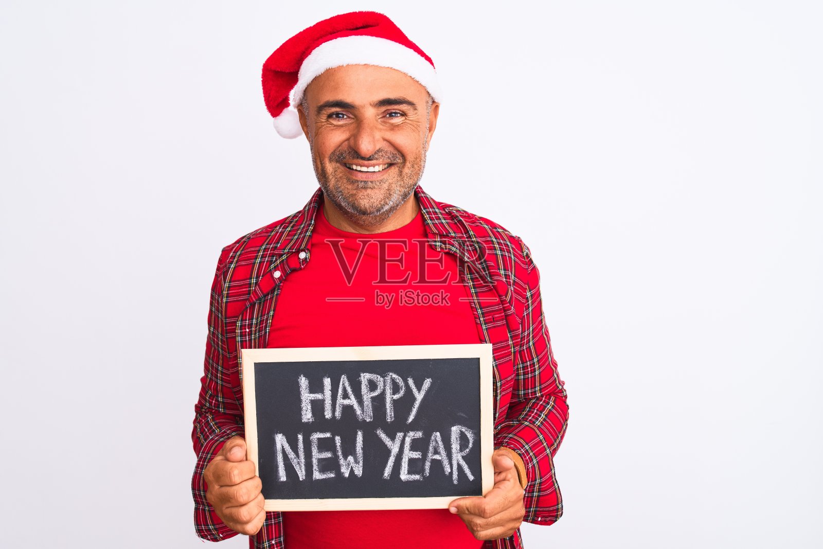戴着圣诞老人帽的人拿着黑板在孤立的白色背景上，一个快乐的脸站着，微笑着自信的微笑露出牙齿照片摄影图片