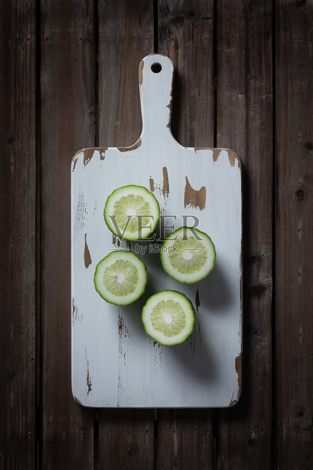 把绿柠檬切在白色的木板上。照片摄影图片