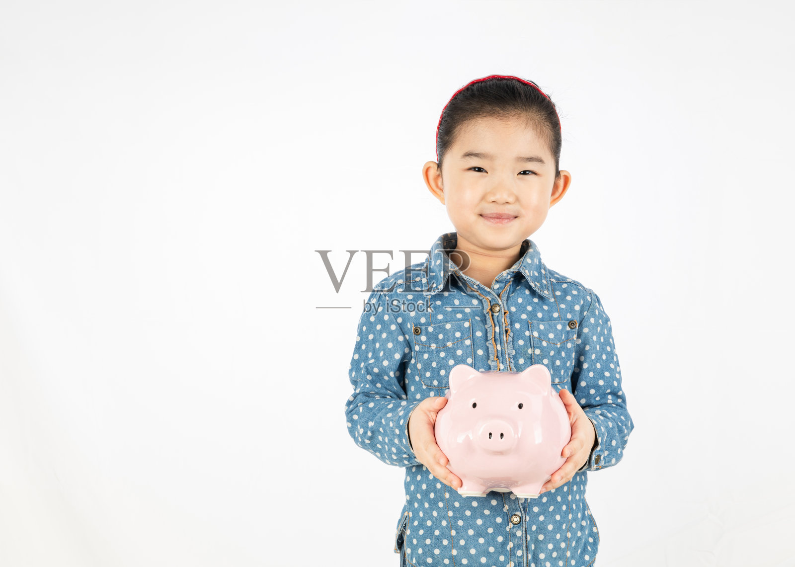 可爱的女孩抱着一个粉红色的存钱罐照片摄影图片