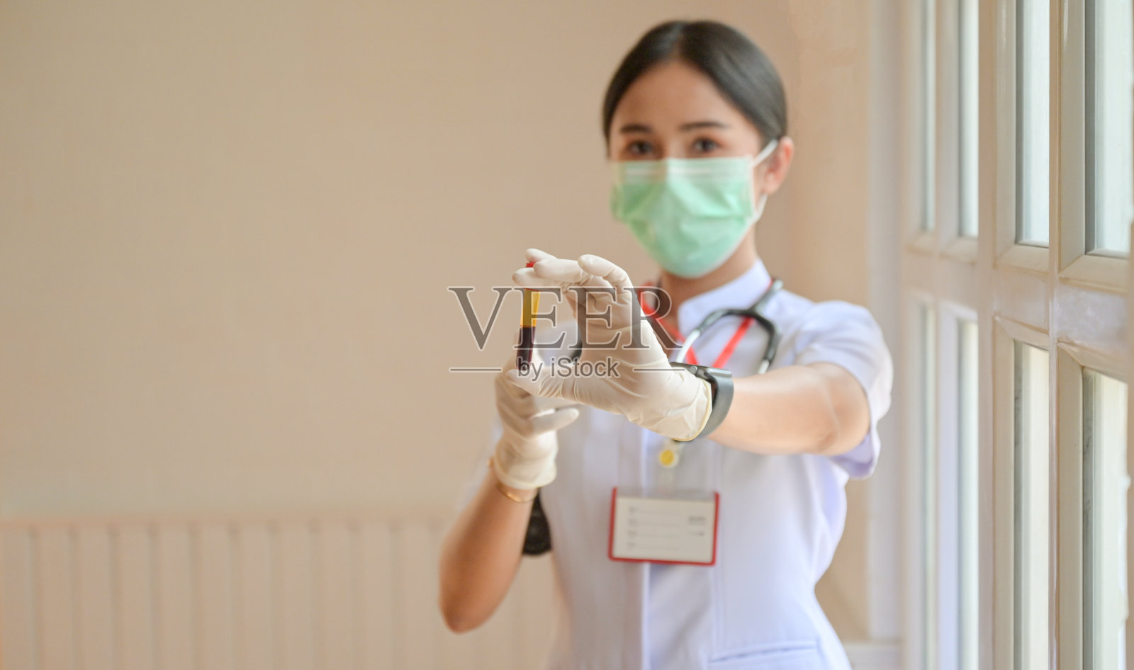 护士戴手套，胸前有血液试管，概念检查covid-19病毒感染情况。照片摄影图片