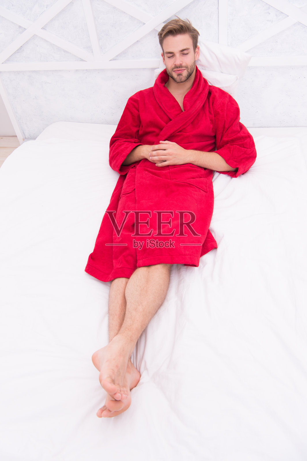 知道如何放松。帅哥躺在床上放松后洗澡。穿着红色浴袍的瞌睡虫早上花时间放松。是休息的时候了照片摄影图片