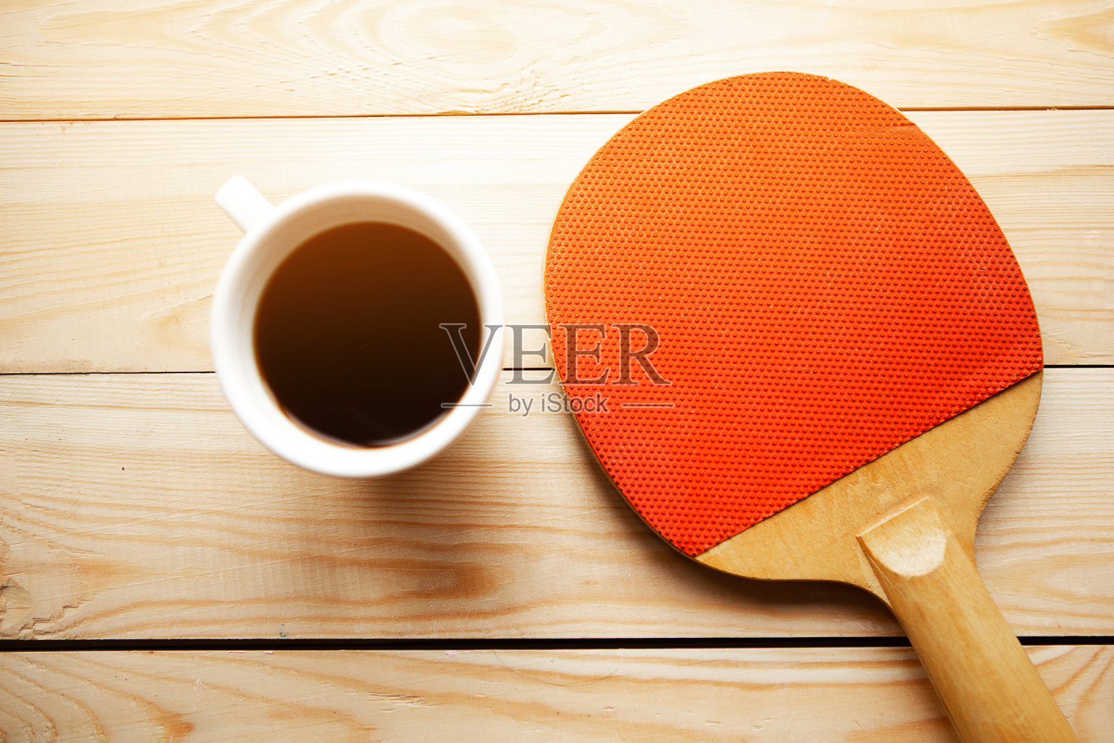 木制背景上的乒乓球拍和咖啡杯。呆在家里的概念照片摄影图片