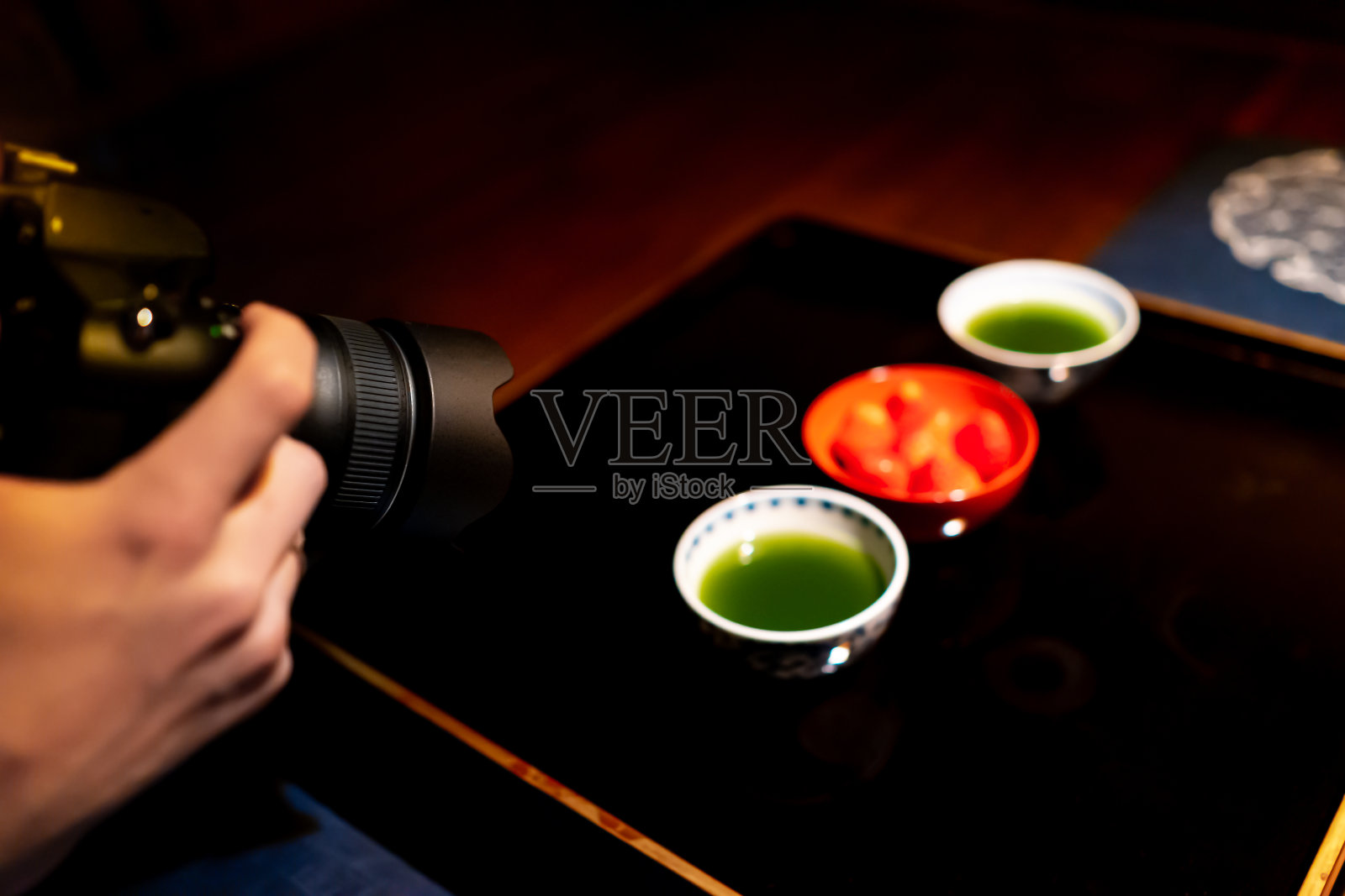在黑漆木桌和甜品盘的背景下，拍摄传统日本杯与抹茶绿茶碗和草莓照片摄影图片