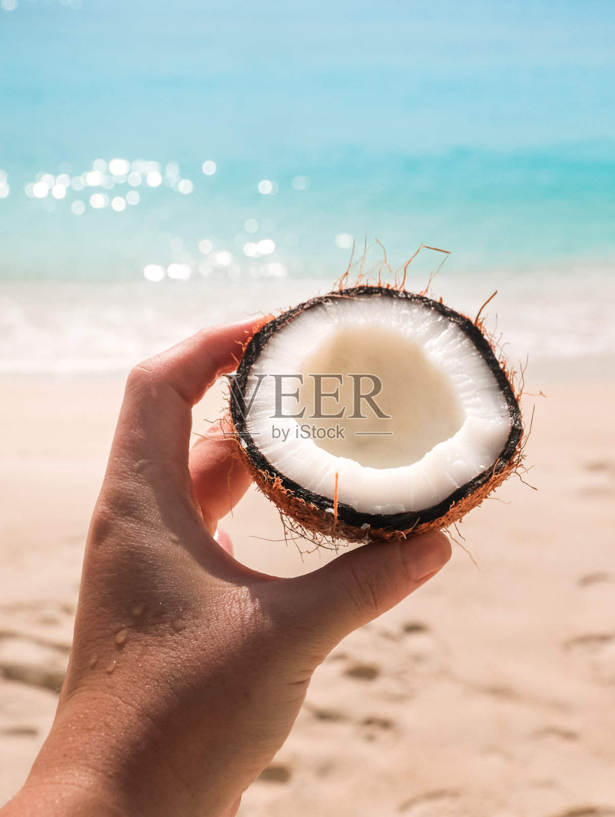 手握椰子在海滩上照片摄影图片