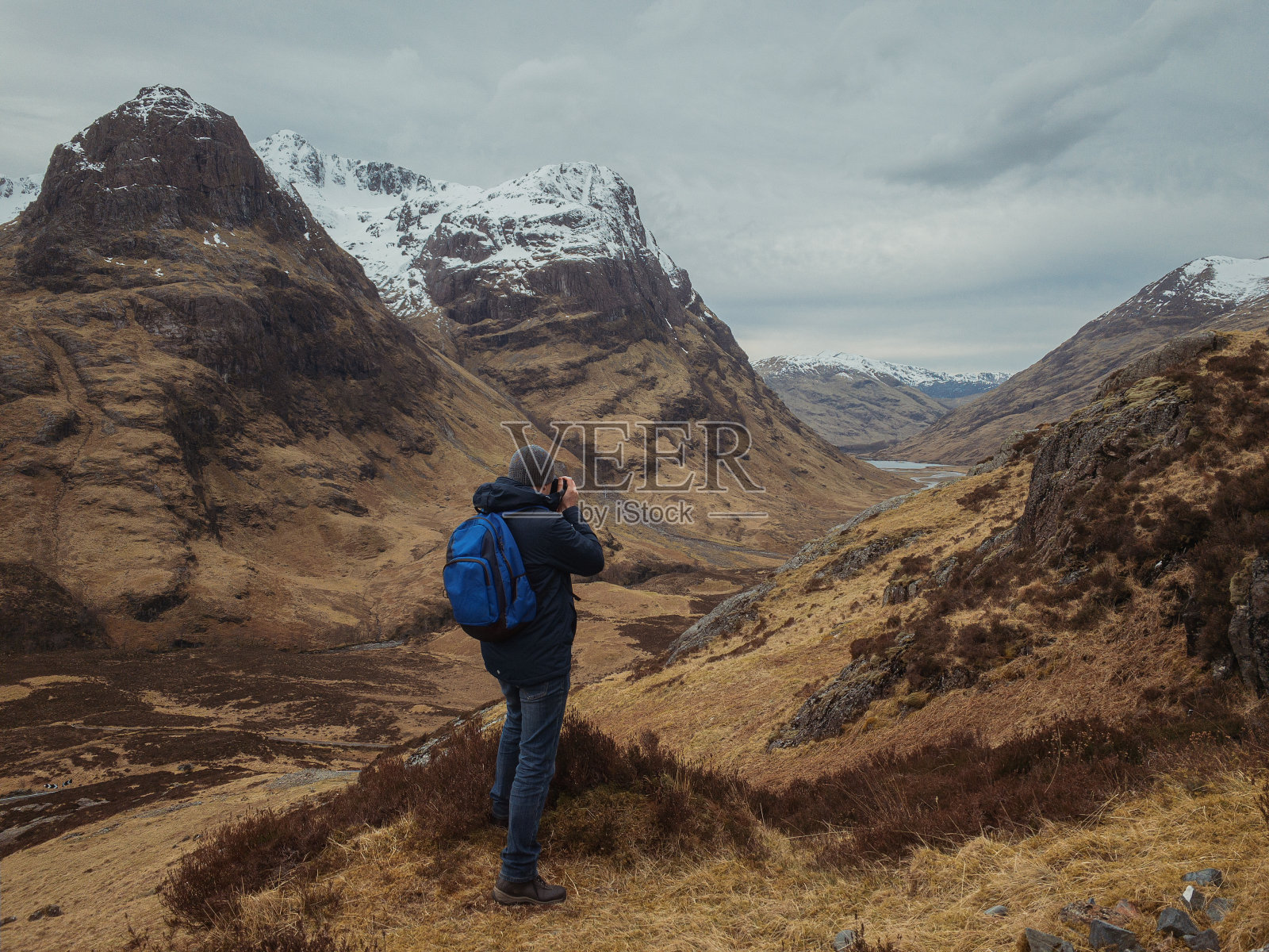 男摄影师背着背包背对着大山，望着山谷照片摄影图片
