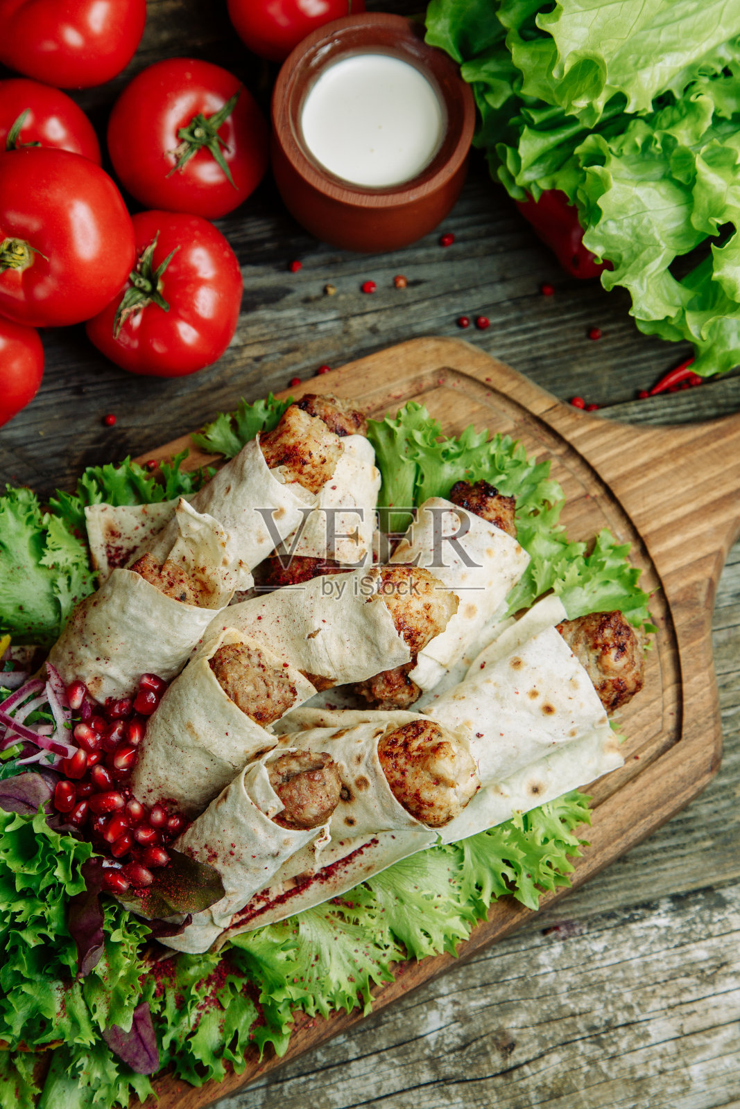 卢拉烤肉串，石榴和洋葱放在木板上。餐厅菜肴在木背景与蔬菜。照片摄影图片