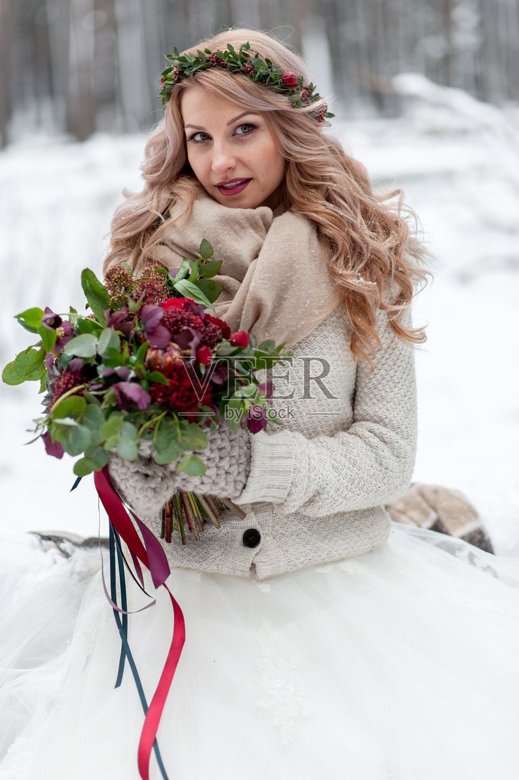 一个带着野花花环的斯拉夫少女。美丽的金发新娘持有一束在冬天的背景。照片摄影图片