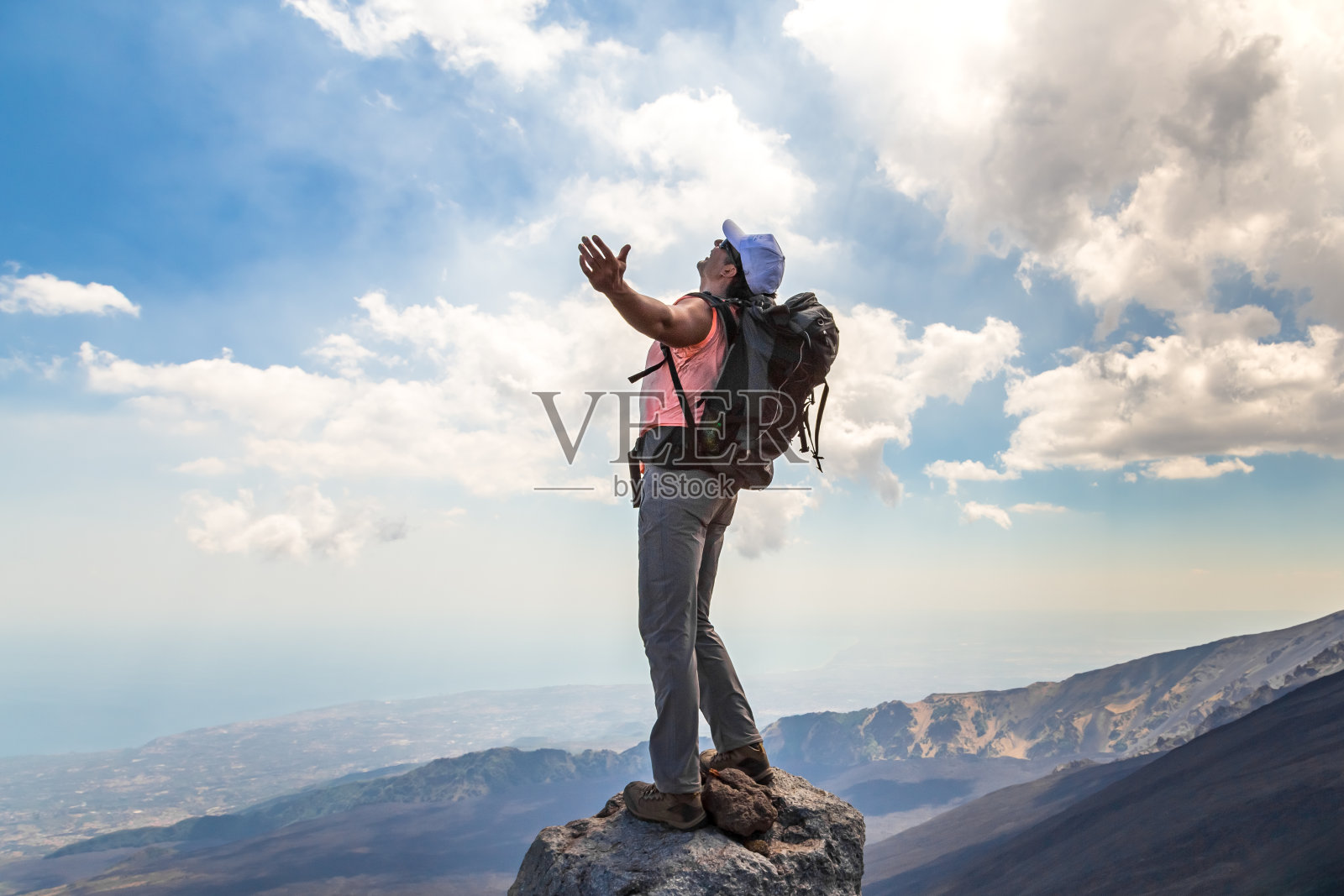 意大利，一名男子在攀登埃特纳火山时张开双臂。照片摄影图片