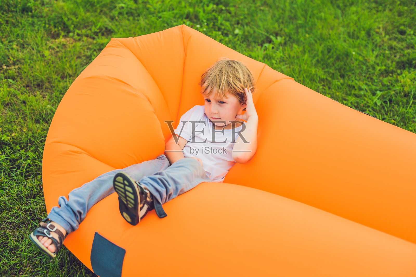 可爱的男孩在公园的沙发上休息。照片摄影图片