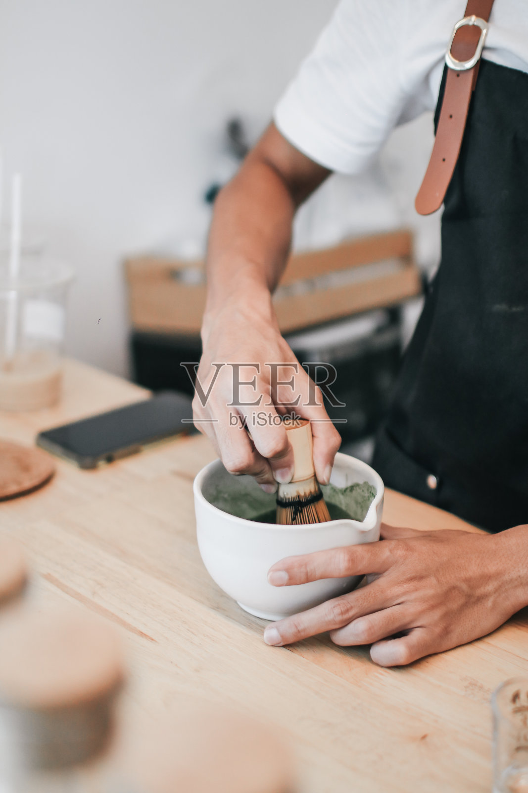竹制的画笔和亚洲咖啡馆专业咖啡师制作的放在木托盘上的抹茶绿茶茶杯。在白色陶瓷碗中搅拌绿茶粉。东方茶道照片摄影图片