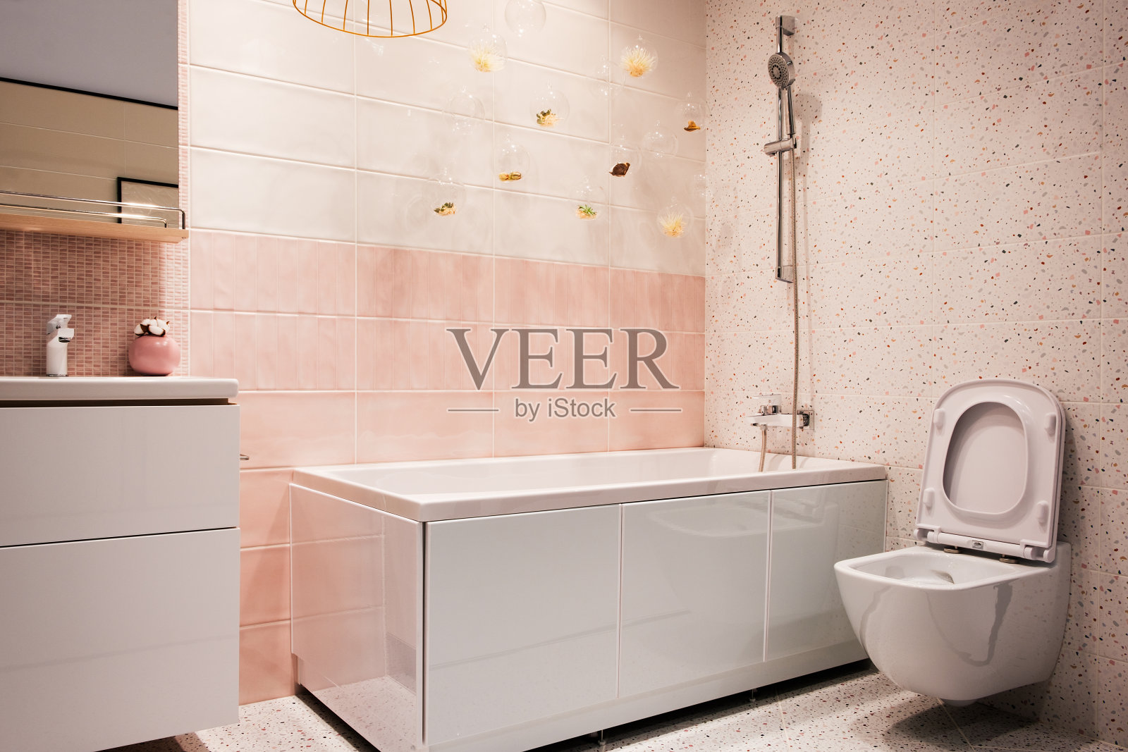 白色和粉色色调的现代浴室内饰，悬挂马桶，水槽，浴缸，水龙头，镜子，淋浴器，家具和配件。照片摄影图片