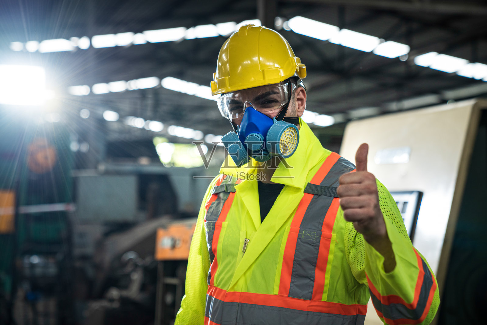 在工业中工作的工程师。亚洲肖像的一个年轻的工程师男子戴着一个安全帽显示拇指向上。安全事故用黄色硬质安全帽、安全护目镜和卫生口罩。照片摄影图片