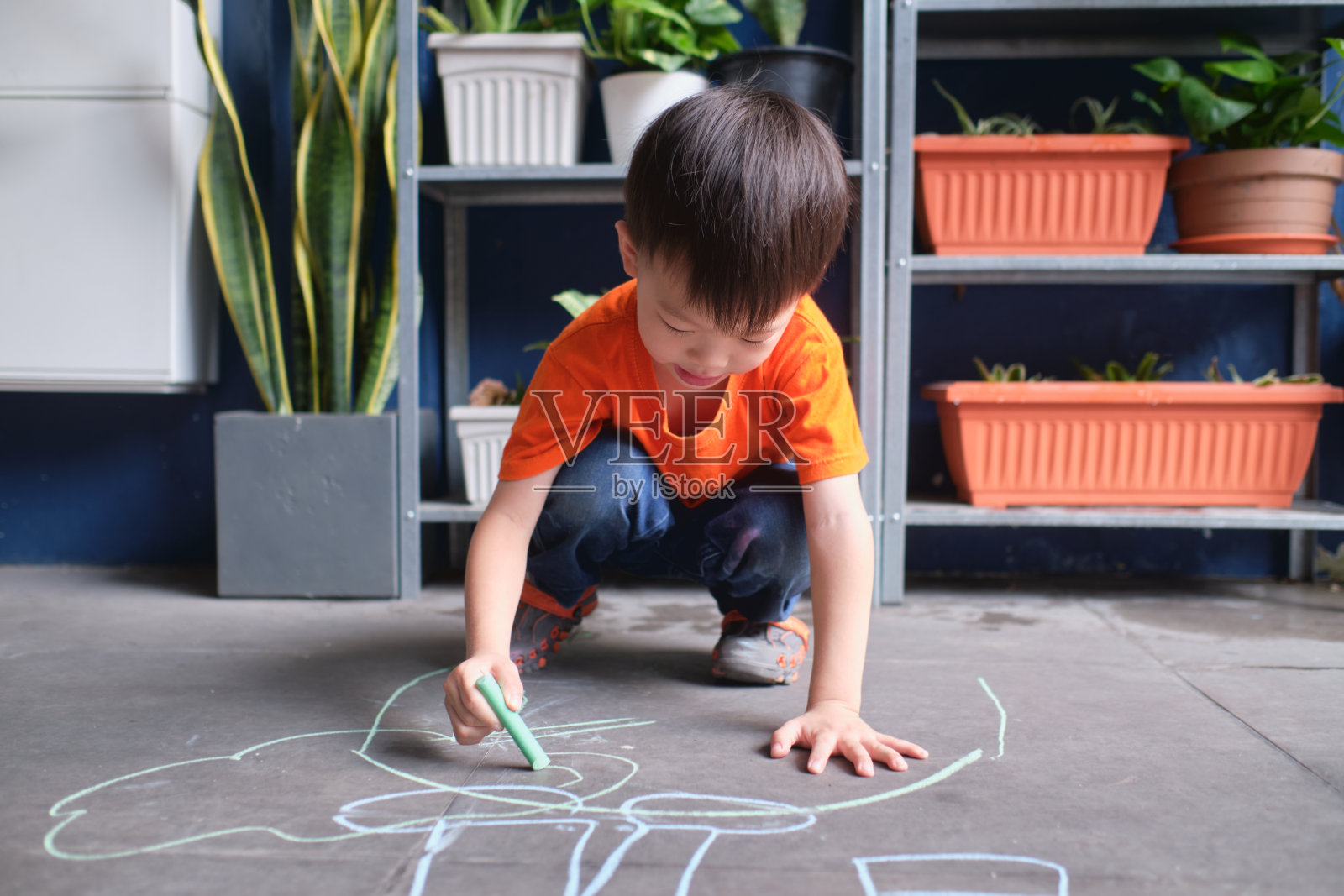 亚洲幼童在家里的车库用彩色粉笔画画，小孩子独自玩耍，儿童户外活动照片摄影图片