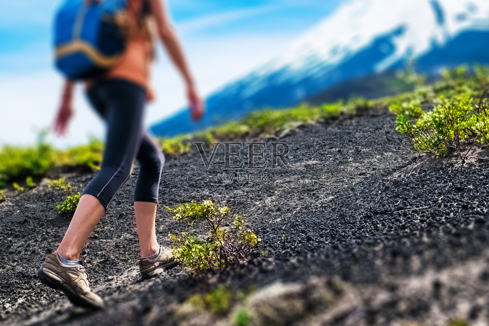 年轻女子徒步行走在松散的岩石小径上，背景是火山的斜坡照片摄影图片