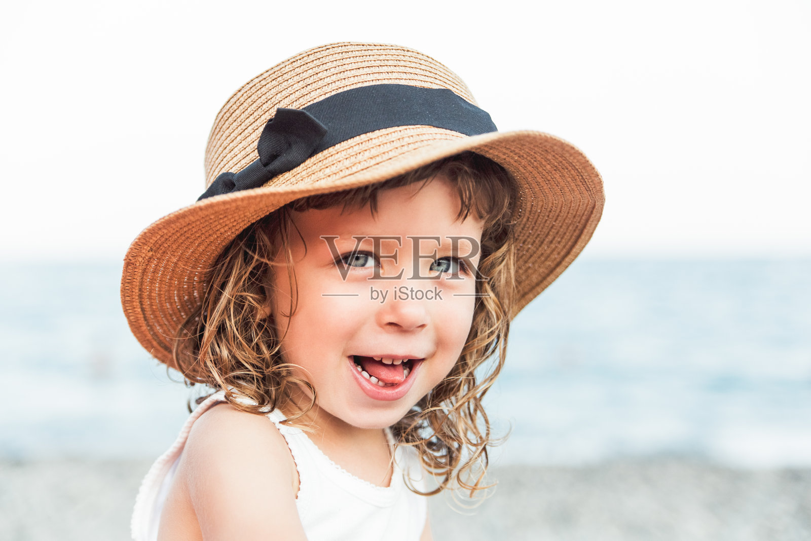 滑稽的孩子女孩的肖像在海滩上戴着帽子与海景。假期,夏季的概念照片摄影图片