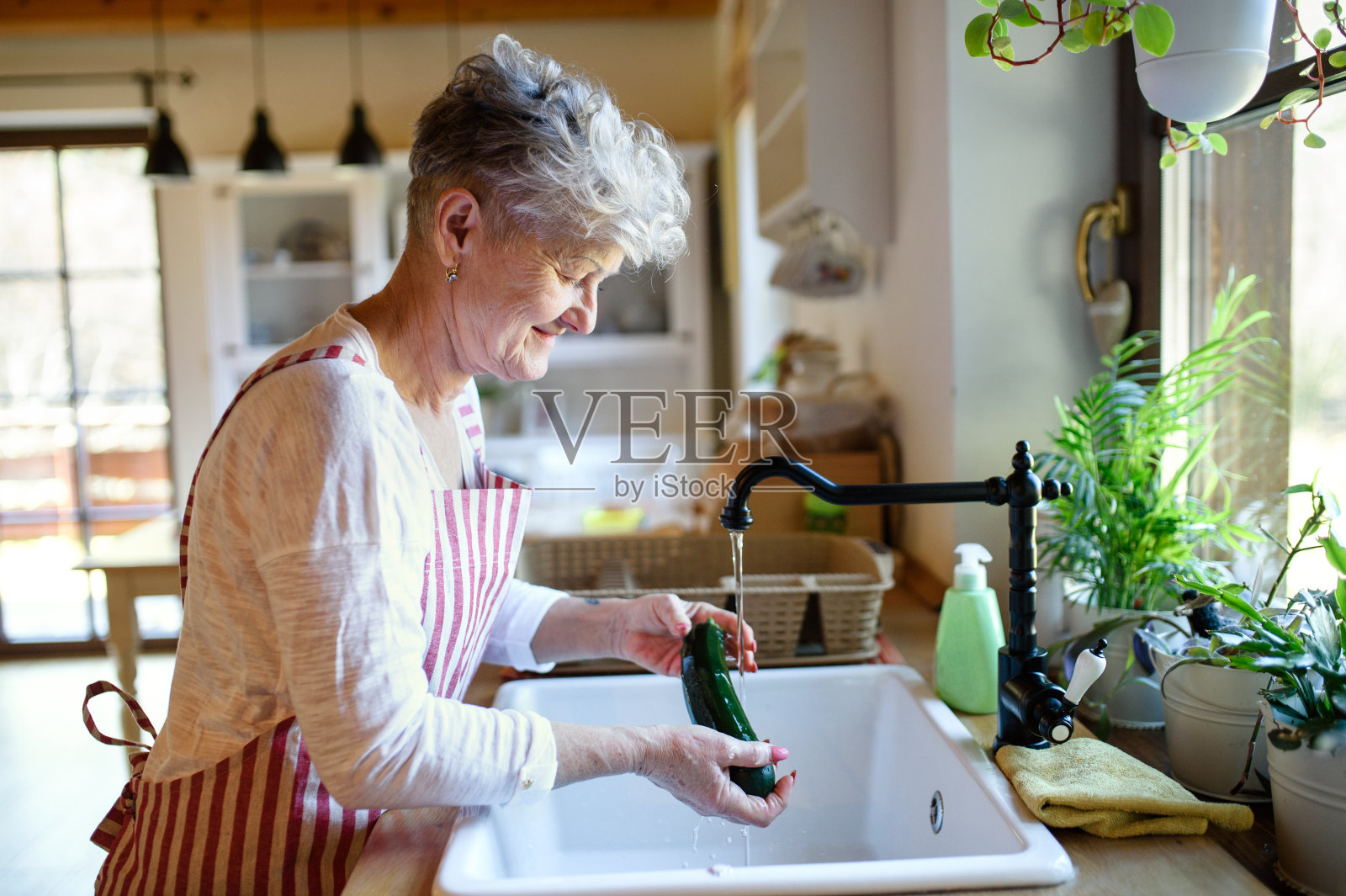 妇女在家做饭时在室内洗蔬菜，冠状病毒概念。照片摄影图片