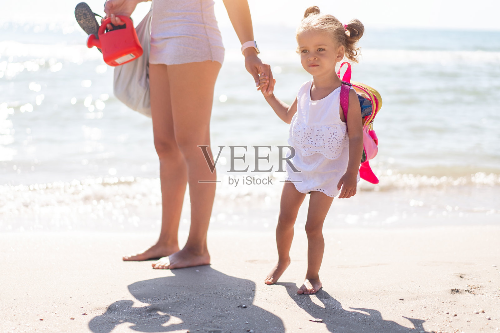 炎炎夏日，年轻的白人母亲带着小女儿沿着海边散步。暑期家庭度假概念。友谊母亲和孩子。照片摄影图片