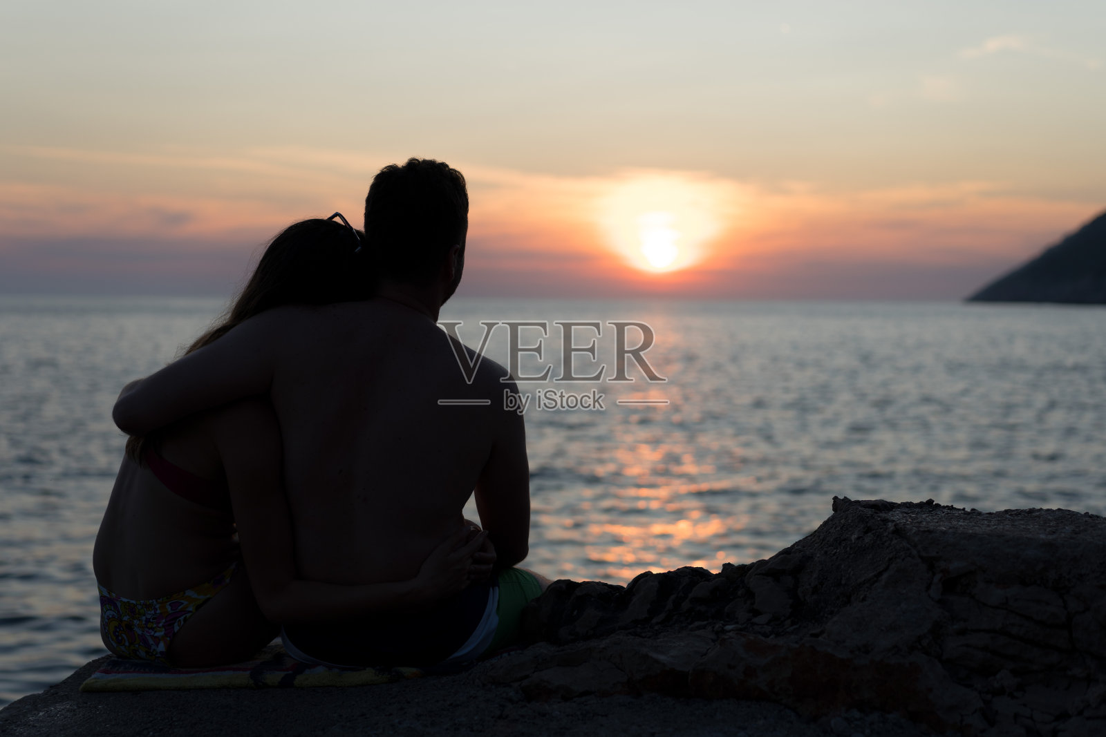 一对年轻夫妇在海滩上看日落的剪影照片摄影图片