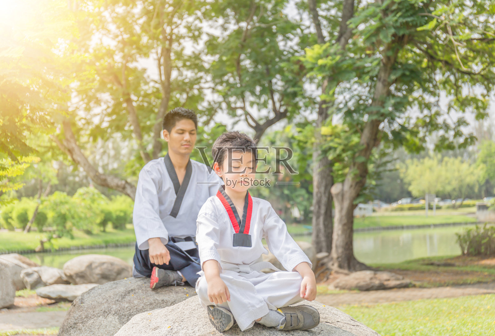 跆拳道男子和孩子坐在公园的石头上冥想照片摄影图片