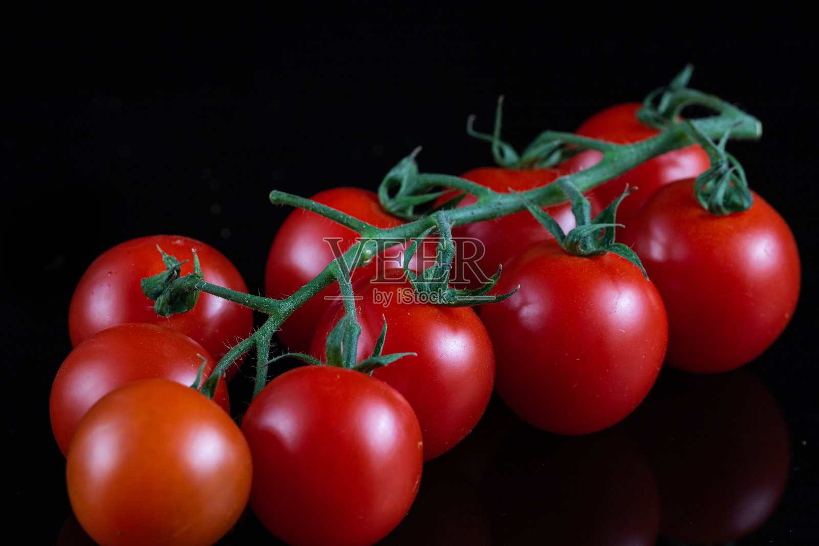 在黑色的桌子和黑色的背景上的一个新鲜和生的樱桃番茄的分支微距摄影照片摄影图片