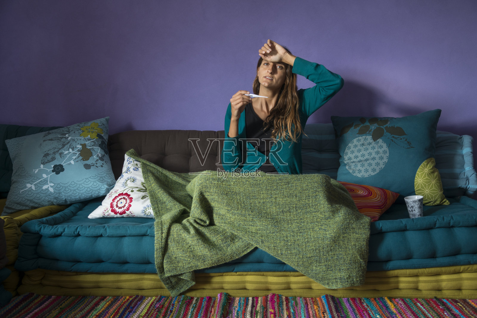 一个患流感的年轻女人躺在沙发上照片摄影图片