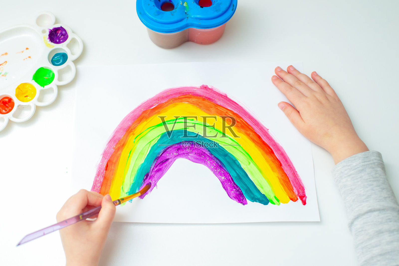 孩子在画彩虹。照片摄影图片
