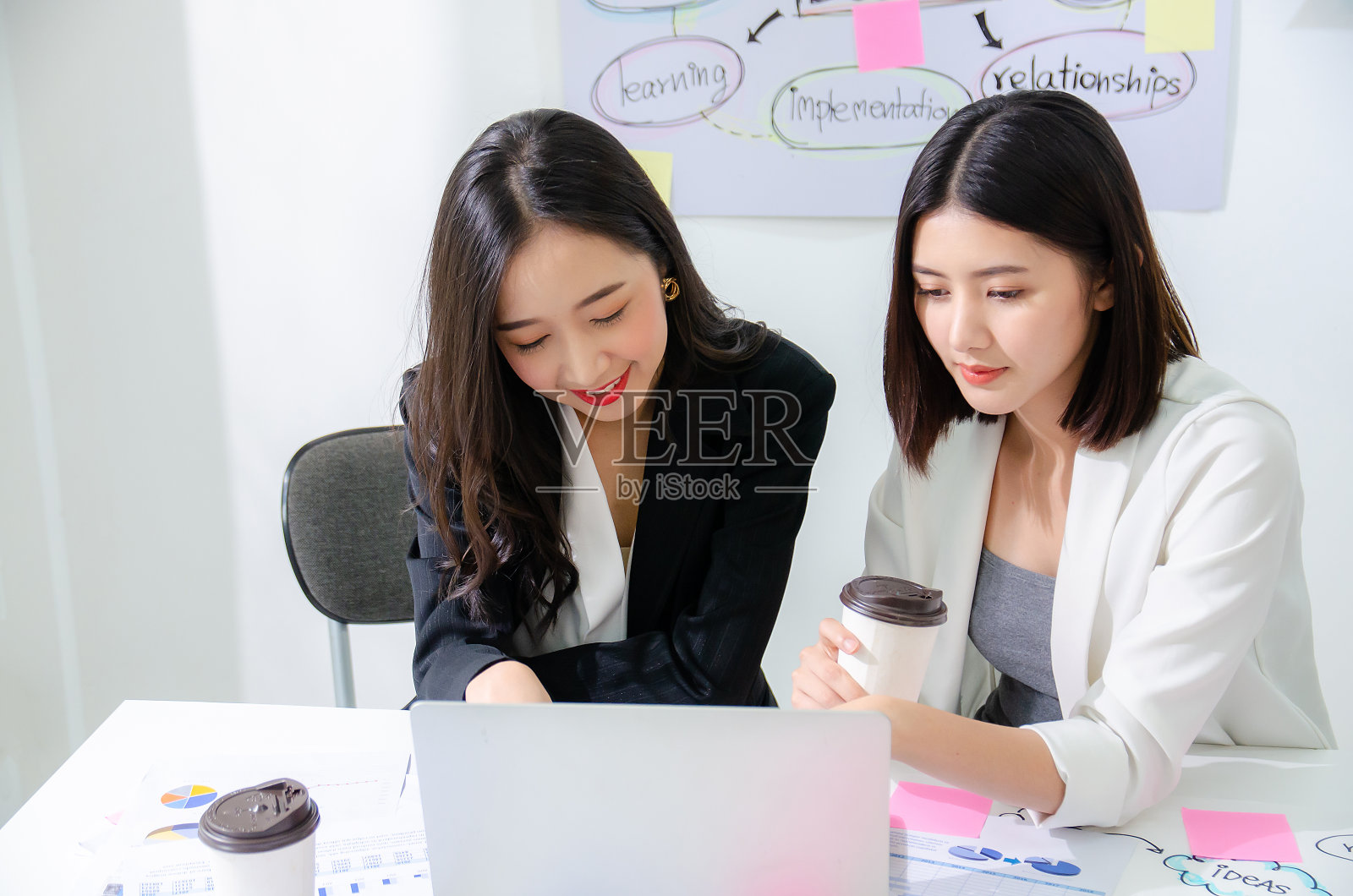 两位努力工作的亚洲年轻女企业家在一台笔记本电脑上一起工作，用严肃专注的表情，高视角阅读屏幕照片摄影图片