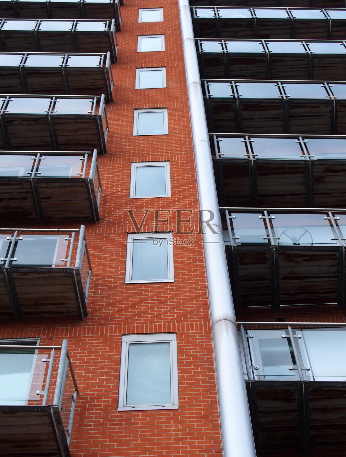向上看的现代公寓建筑与窗户在砖墙和玻璃阳台照片摄影图片