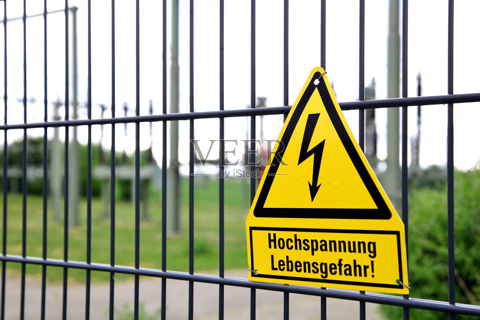 有安全说明的围栏。Sign: Hochspannung - Lebensgefahr, engl。高电压-危及生命。背景模糊的高压开关设备照片摄影图片