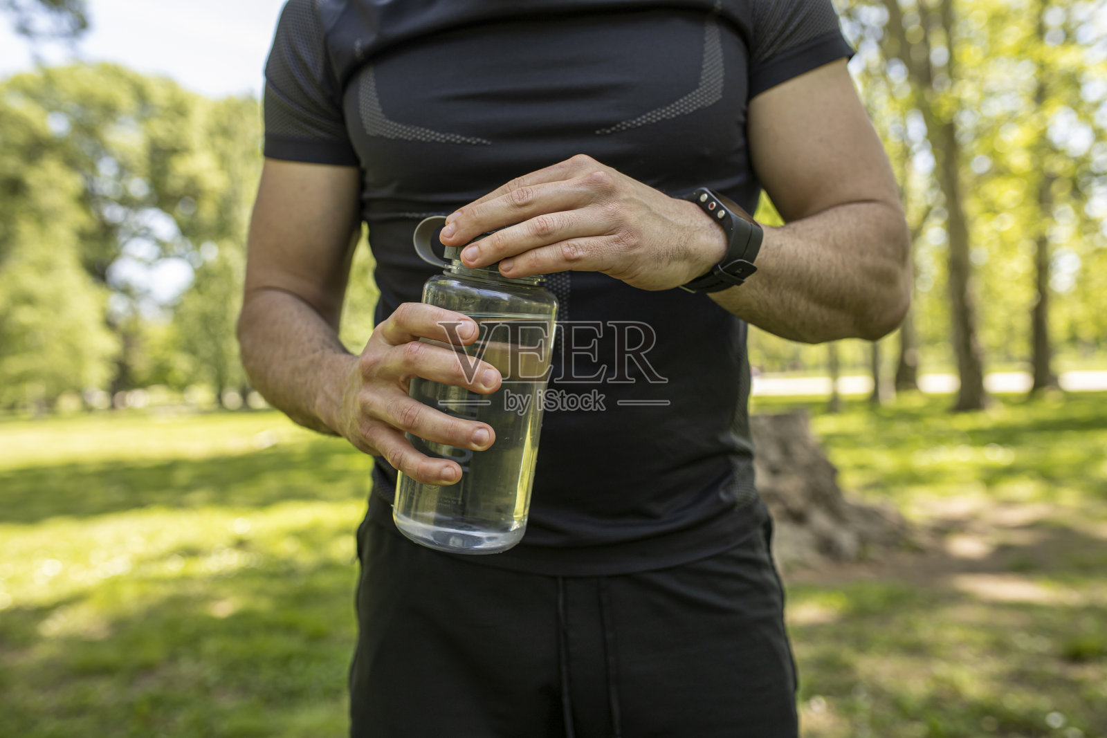 一个拿着水瓶，戴着智能手表的男人照片摄影图片