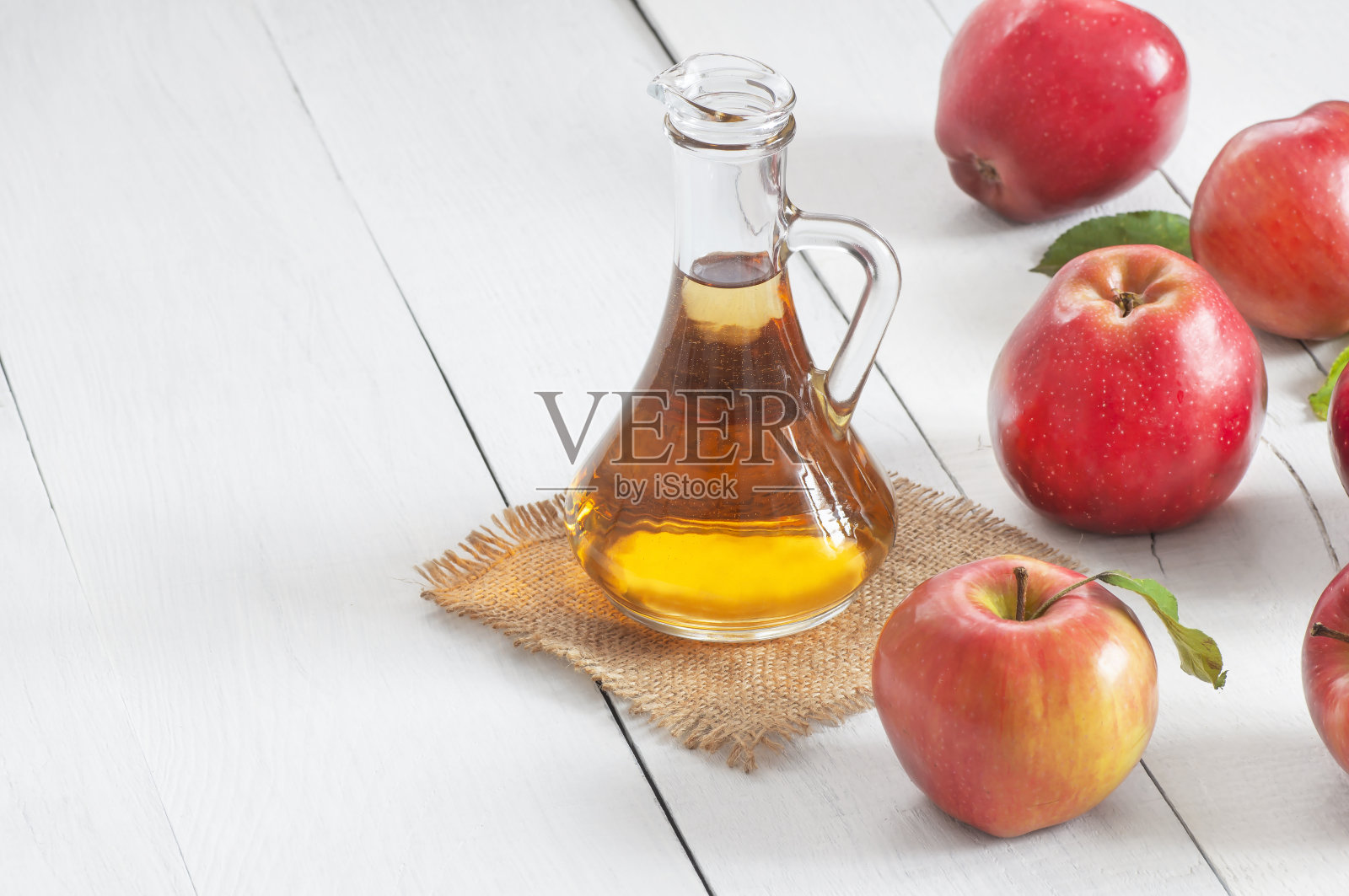 玻璃瓶的有机苹果醋，切片和成熟的新鲜苹果放在白色的木桌上，文字空间照片摄影图片